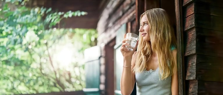 blogartikel_wasser_ist_nicht_gleich_wasser-krumbach_mineralwasser_glas-frau-auf-terasse-header